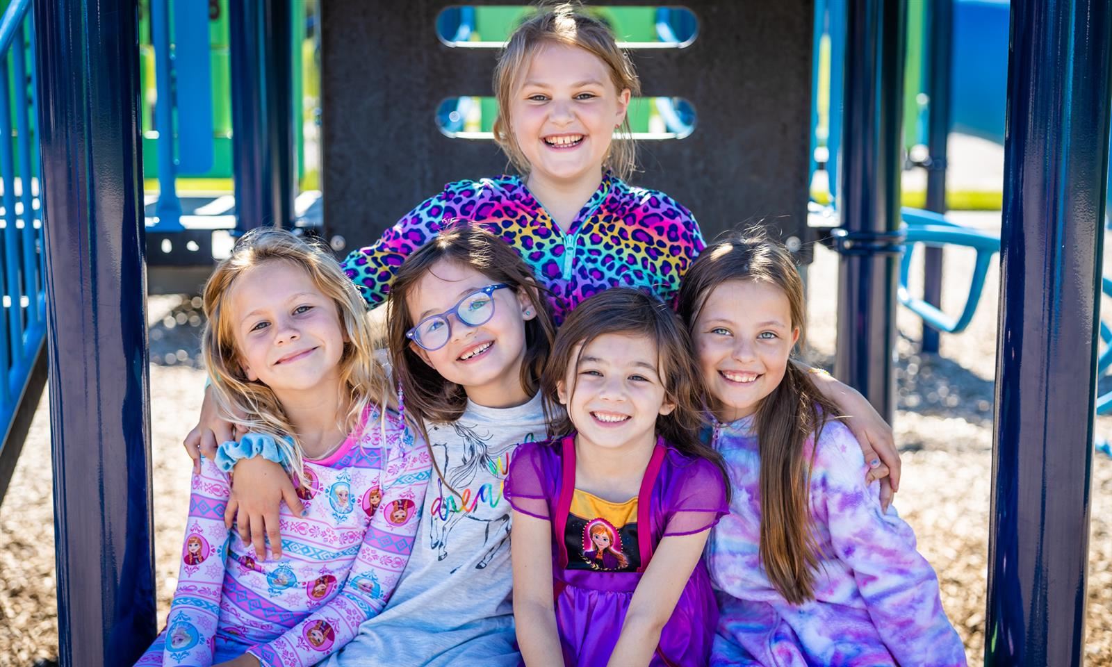 Five girls smile on a playground